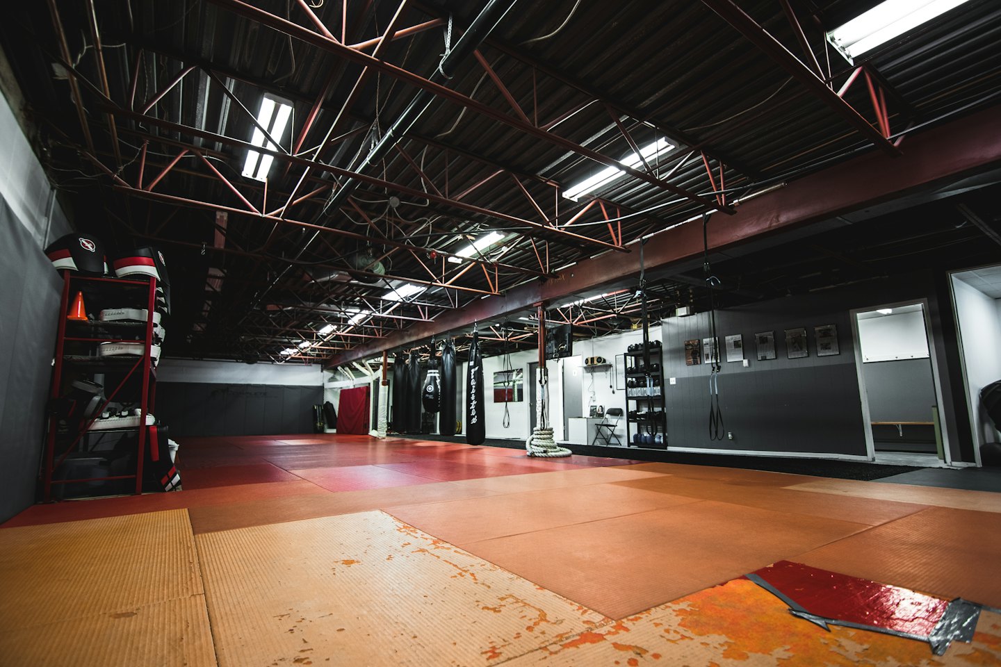 Empty martial arts gym with red beams and equipment.