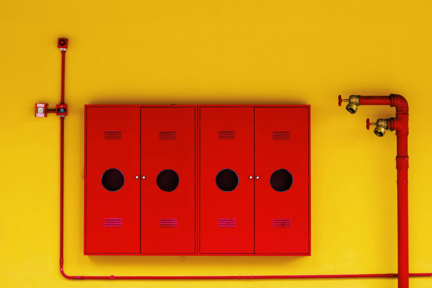 Red fire safety equipment mounted on a yellow wall.